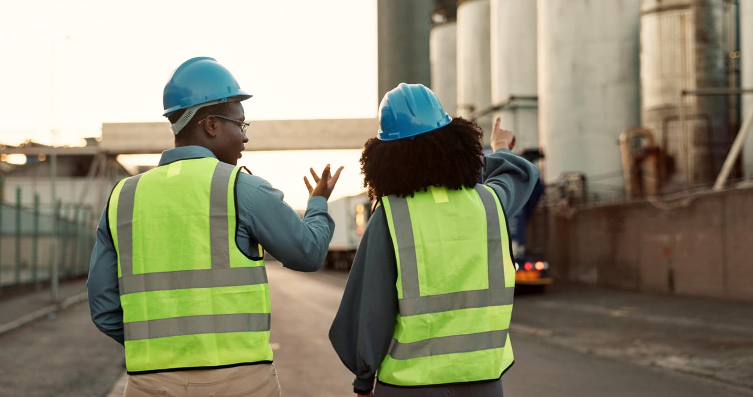 Two professionals wearing hard hats and high-visibility vests during a site inspection