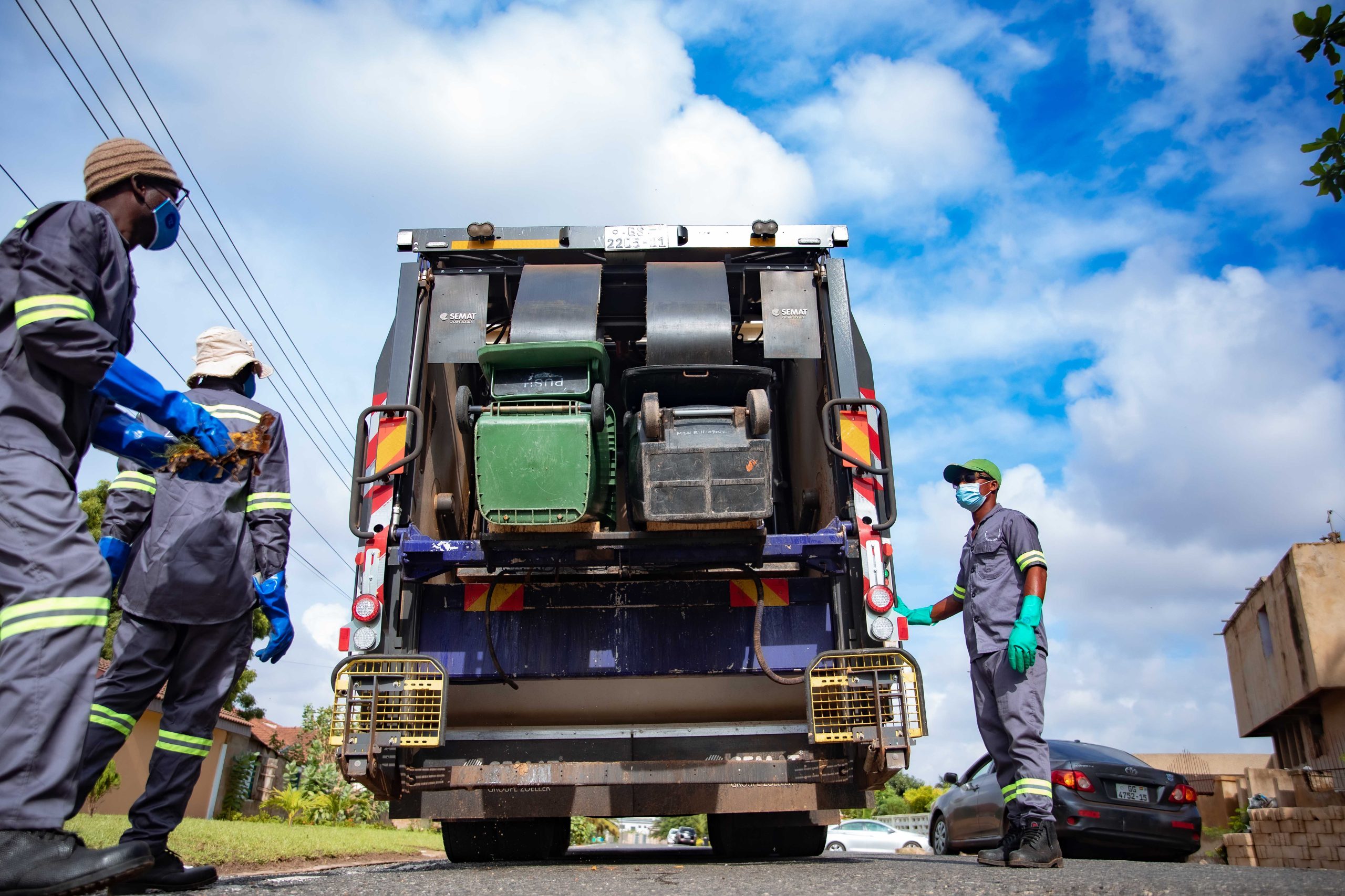 Zoomlion waste collection crew loading bins into a refuse truck in Ghana
