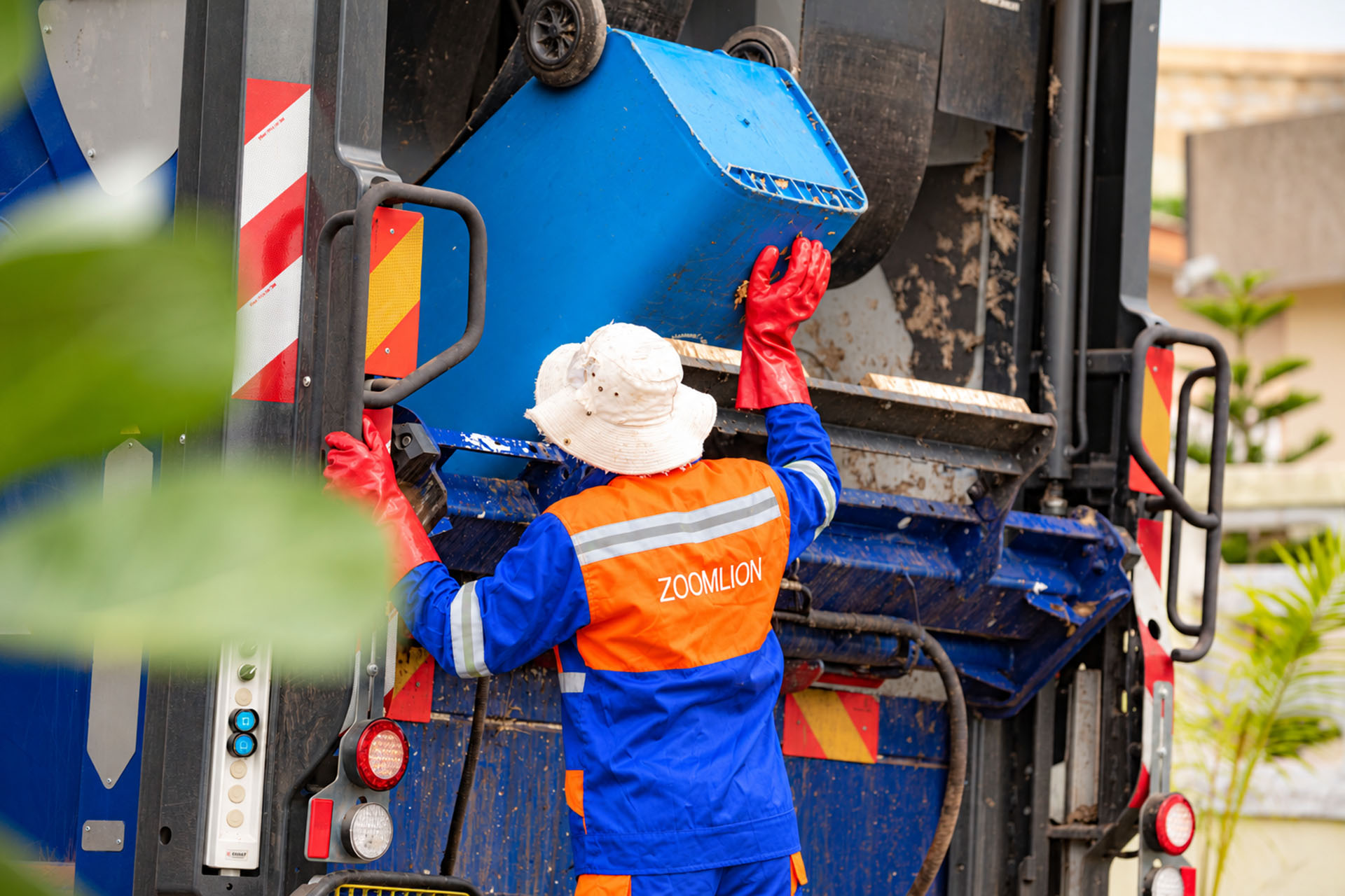 Zoomlion waste-collection crew working beside a refuse truck in Ghana
